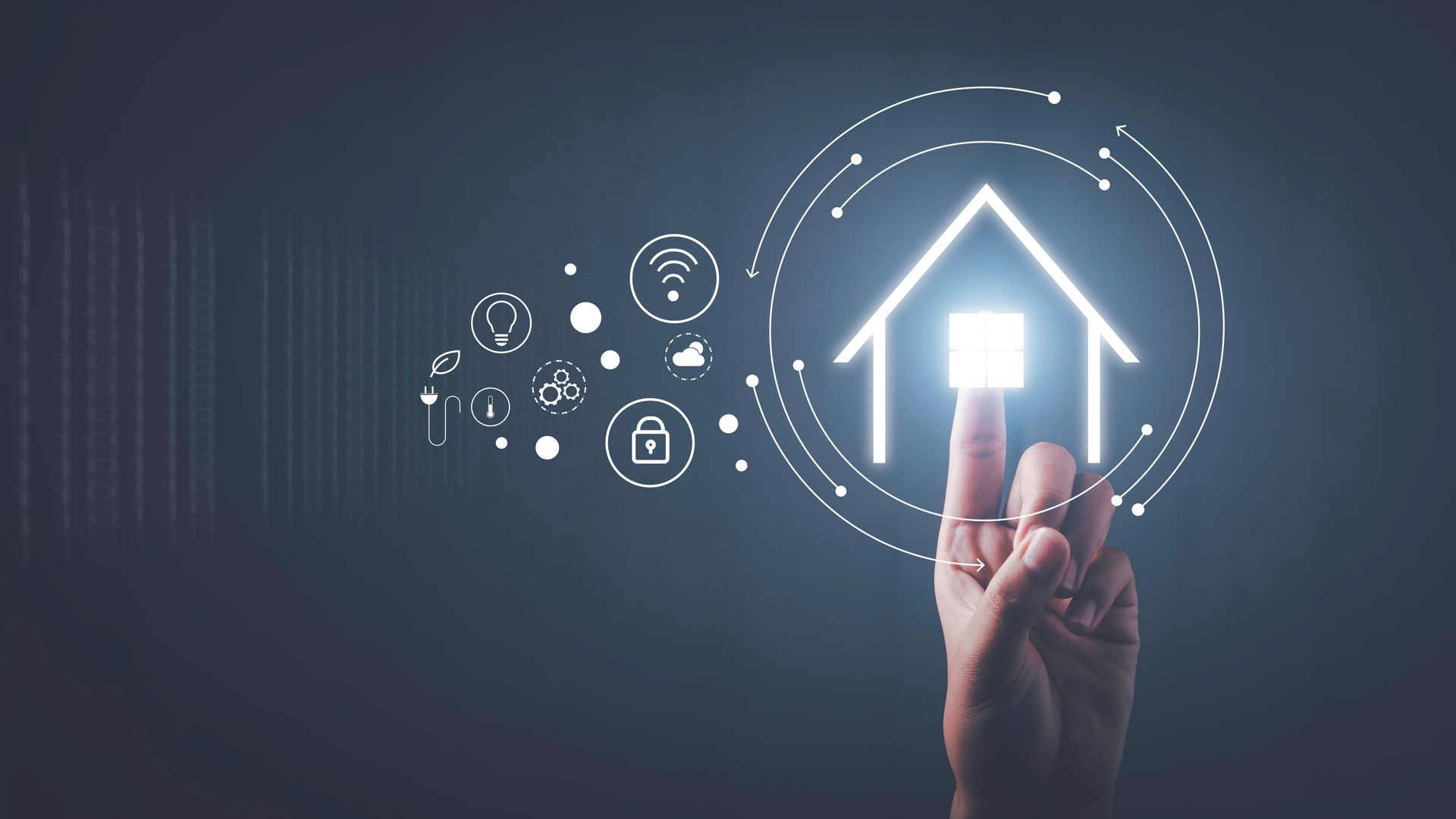 Main appuyant sur une icône de maison lumineuse avec des symboles de maison connectée sur fond sombre.