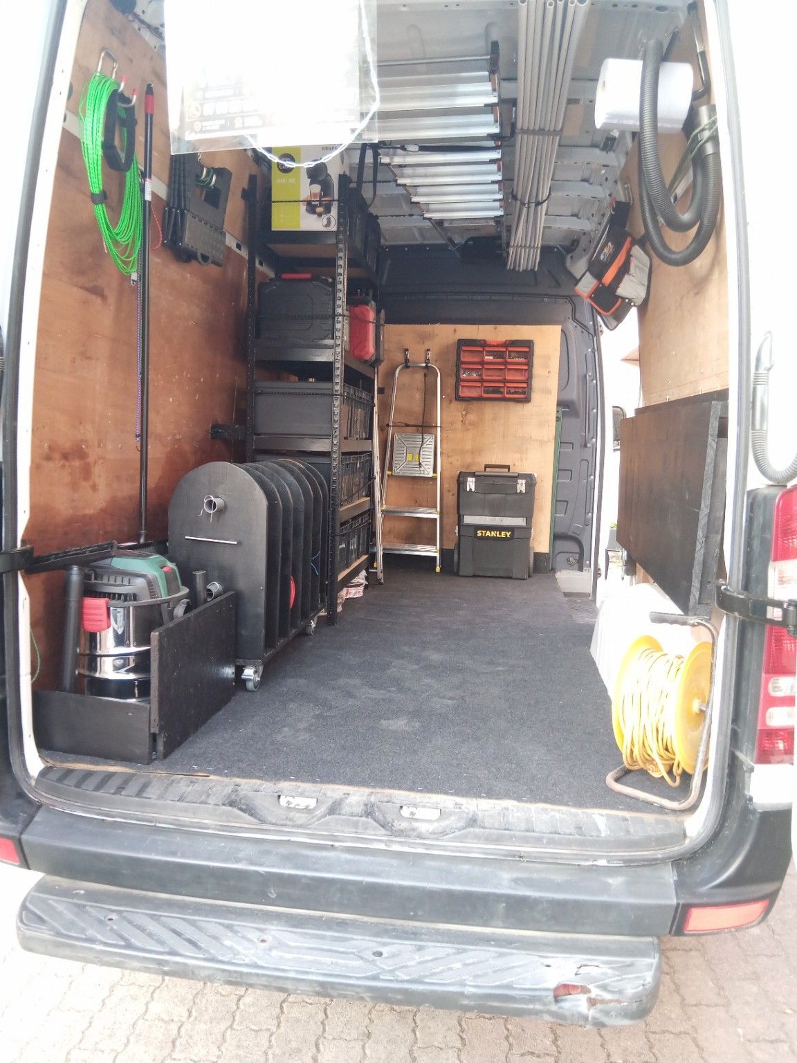 Intérieur ouvert d'une camionnette remplie d'outils, d'étagères et d'équipements aménagés en atelier