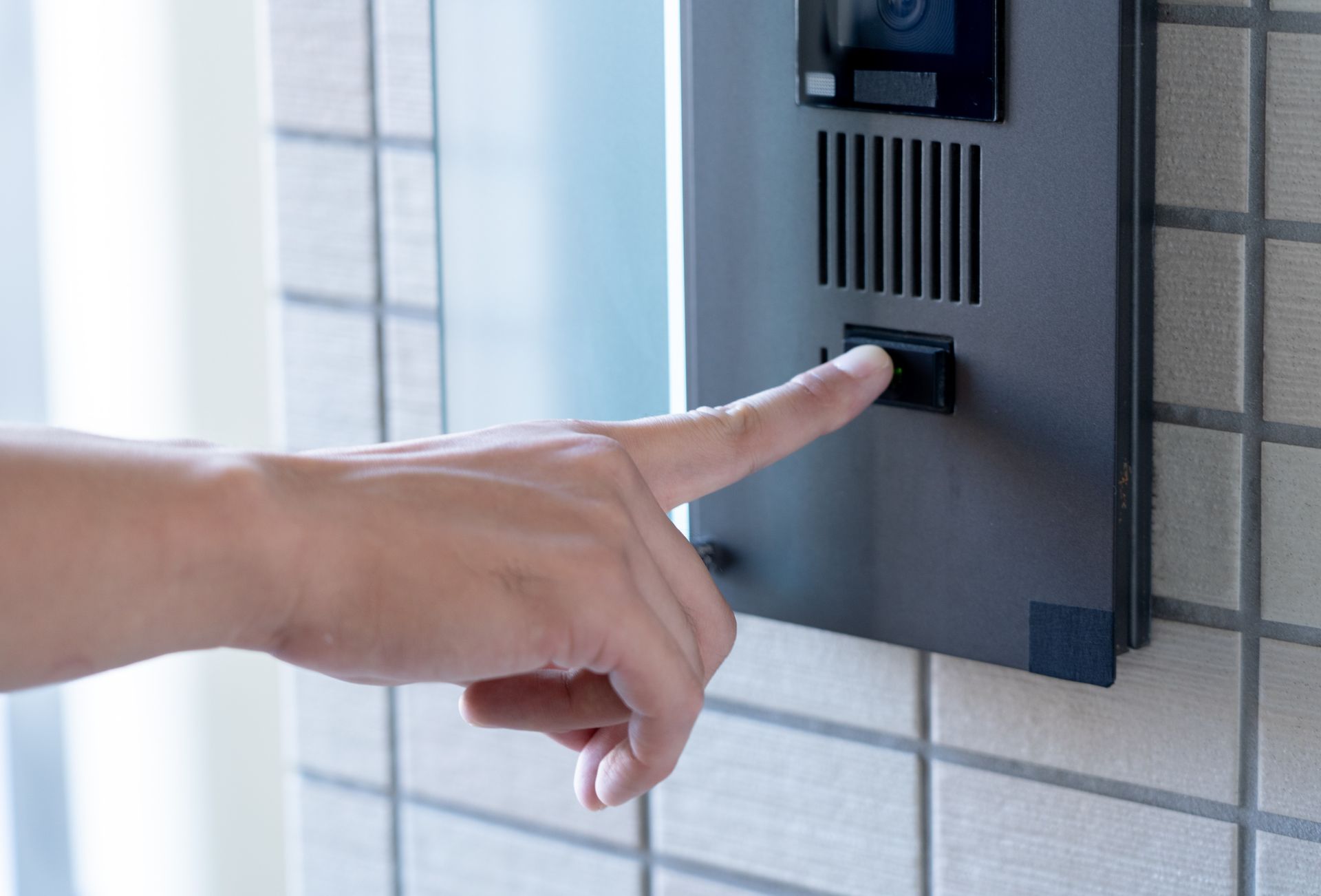 Appuyer sur le bouton d'interphone d'une sonnette murale.