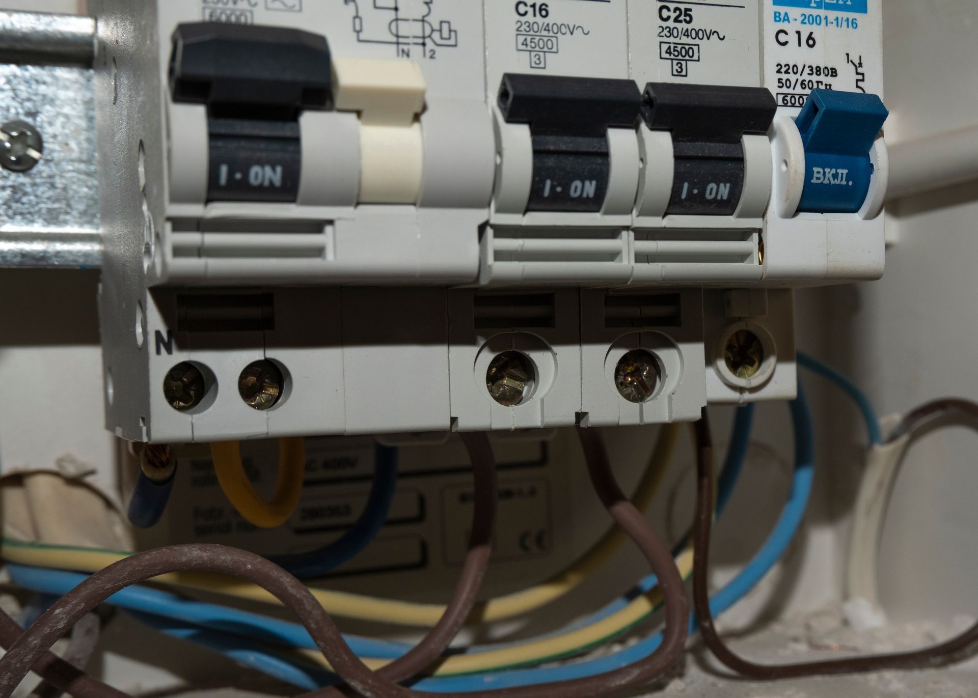 Disjoncteurs électriques dans un panneau avec câblage apparent en dessous.