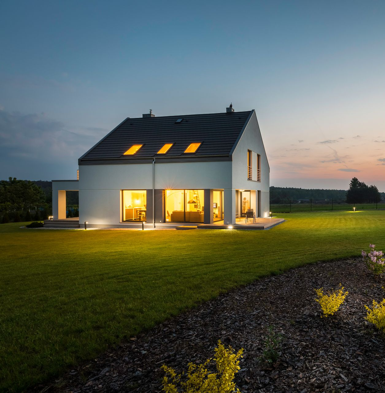 Maison éclairée avec de grandes baies vitrées vue du jardin