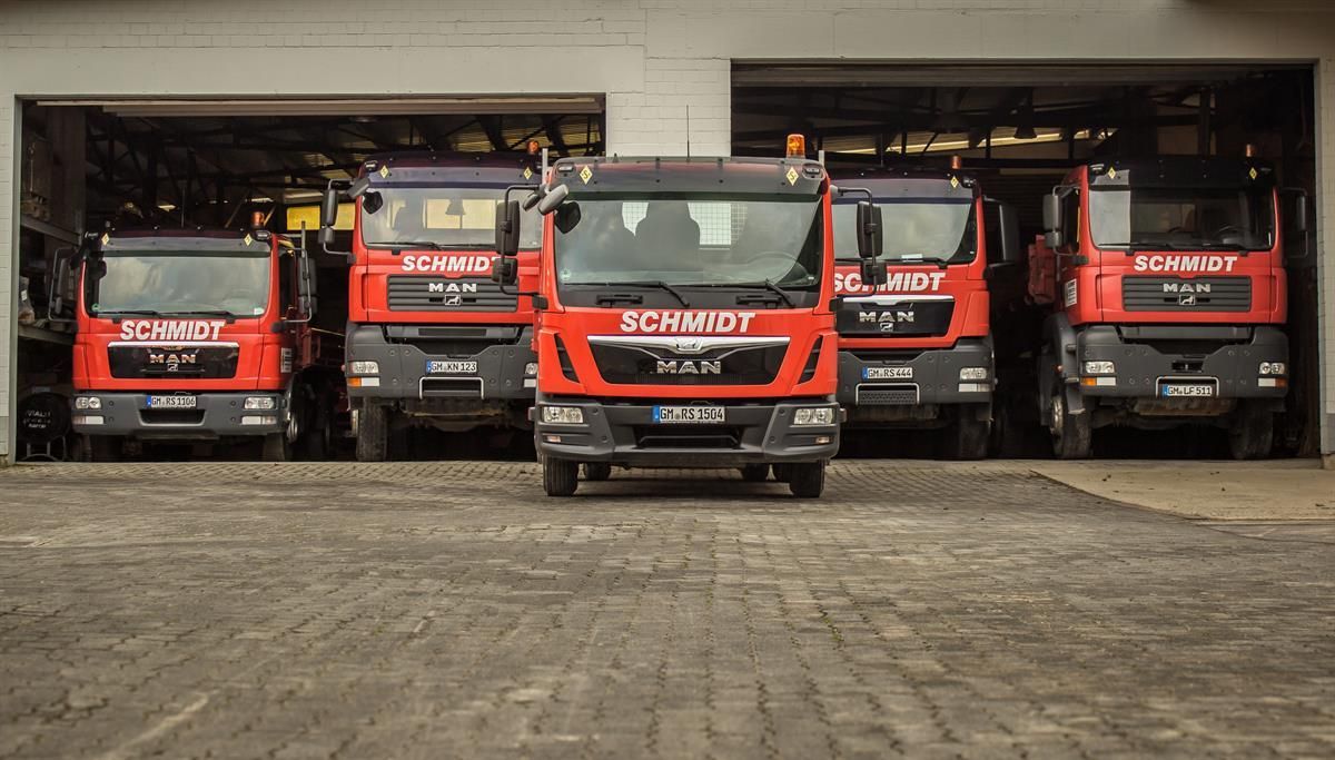 Eine Reihe von Lastwagen parken vor einer Garage mit der Aufschrift „Schmidt“