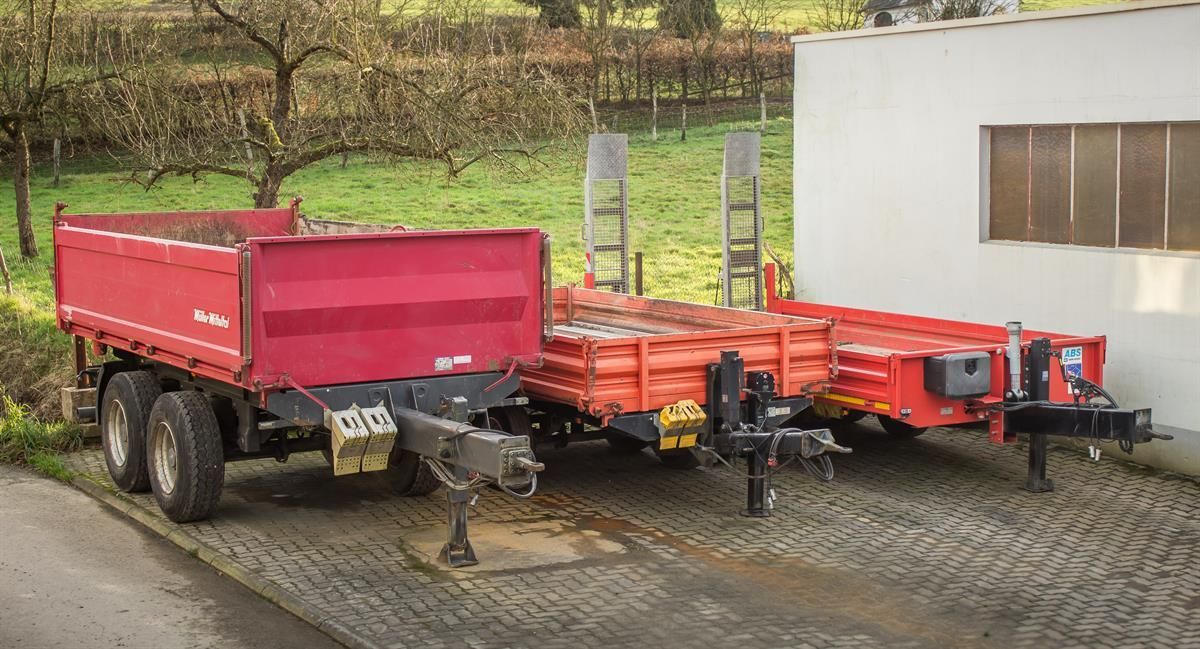 Drei rote Anhänger stehen vor einem Gebäude
