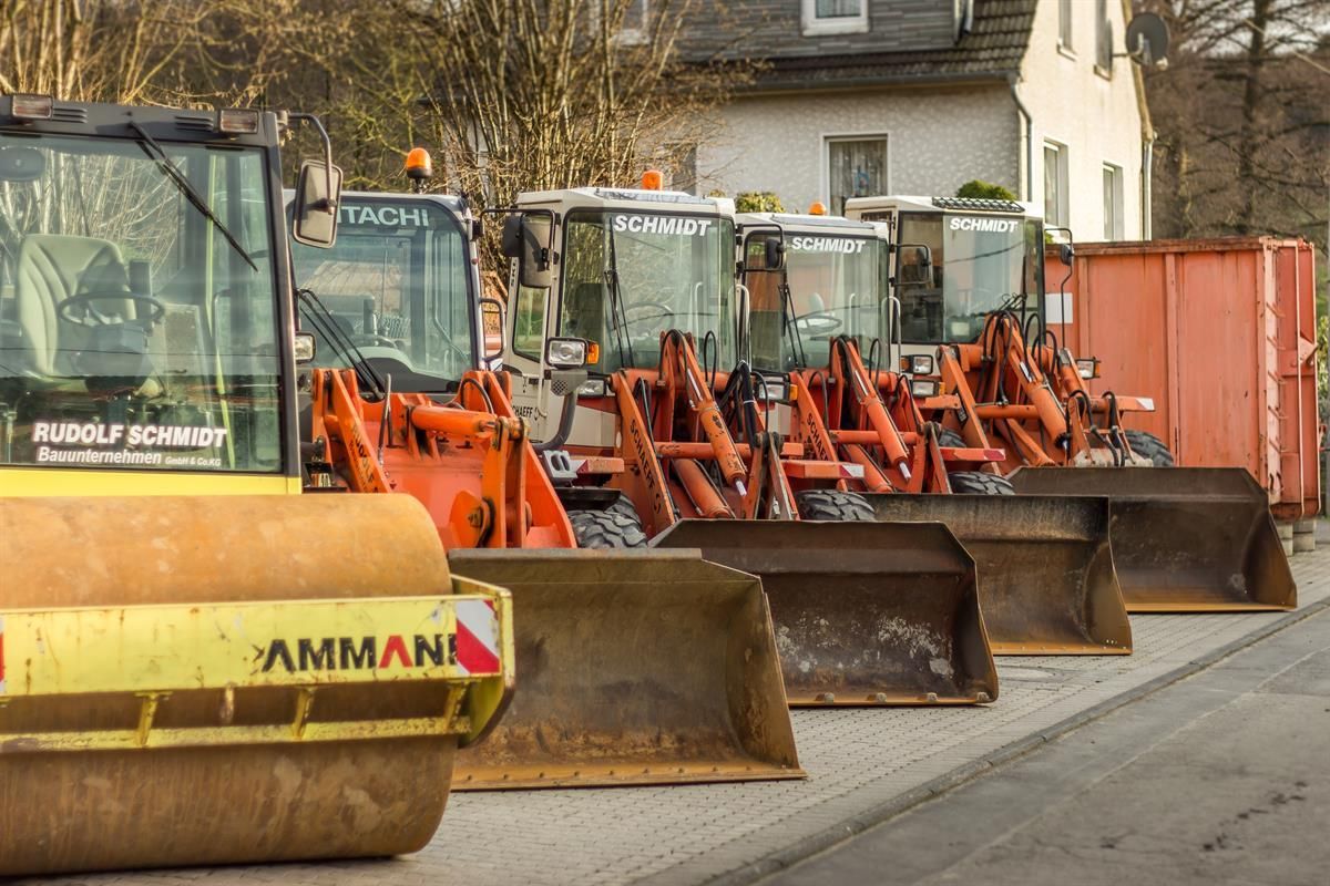Eine Reihe von Ammann Baufahrzeugen parken am Straßenrand