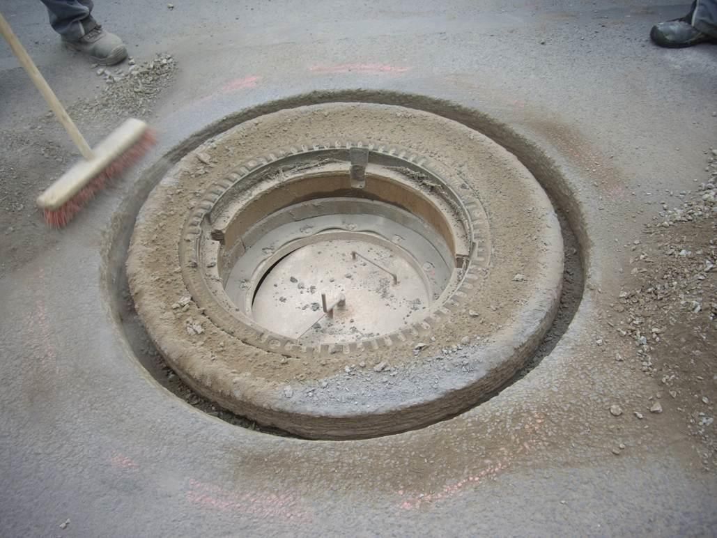 Ein Kanaldeckel wird mit einem Besen gereinigt