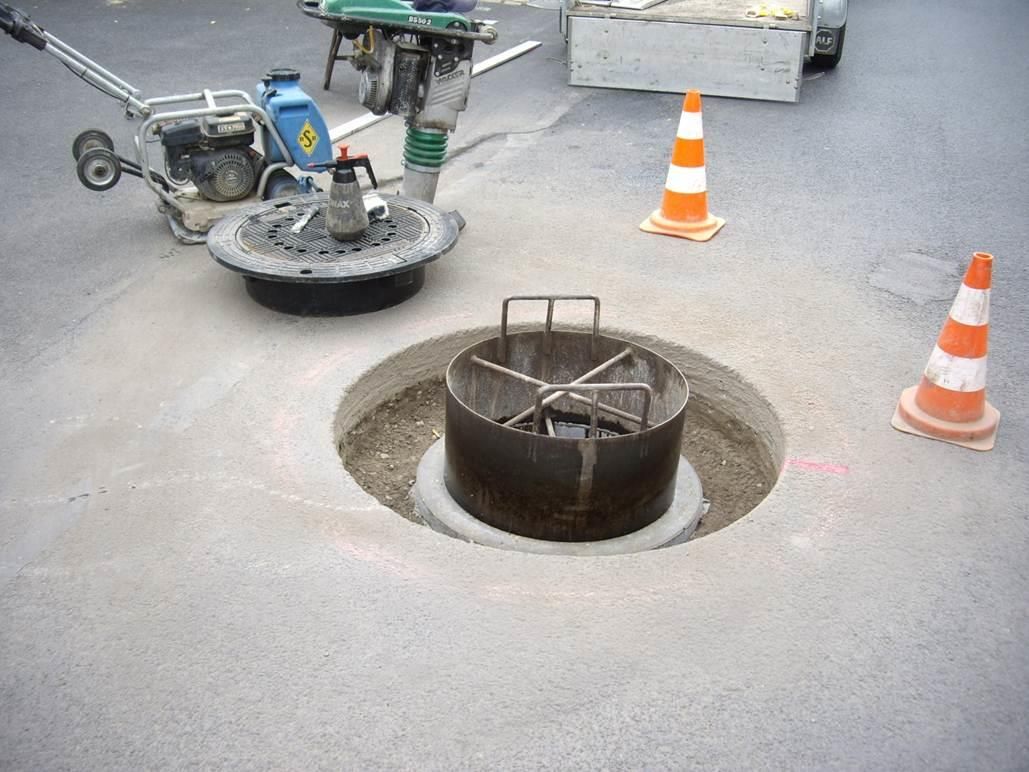 In der Mitte der Straße wird ein Kanaldeckel installiert