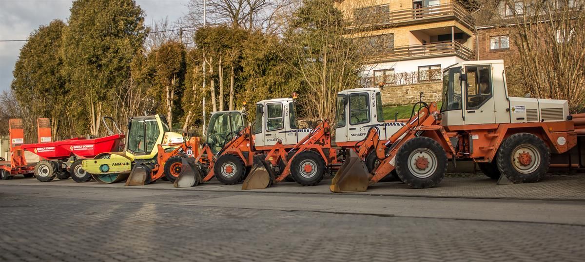 Auf einem Parkplatz steht eine Reihe von Baufahrzeugen.