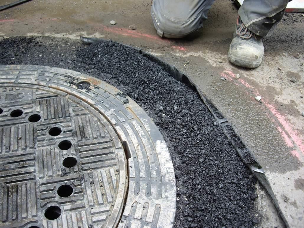 Ein Kanaldeckel mit Löchern darin und eine Person, die daneben steht