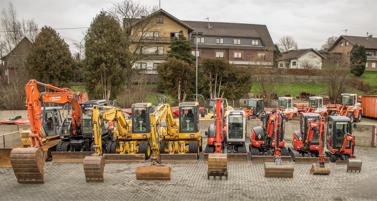 Eine Reihe von Baufahrzeugen parkt auf einem Schotterplatz