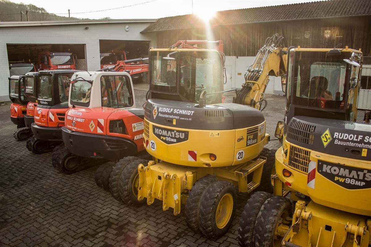 Eine Reihe von Komatsu-Traktoren sind vor einem Gebäude geparkt