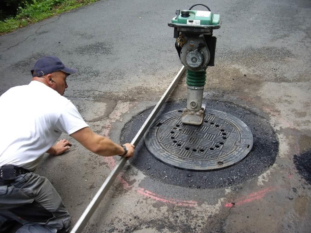 Ein Mann misst einen Kanaldeckel mit einem Lineal