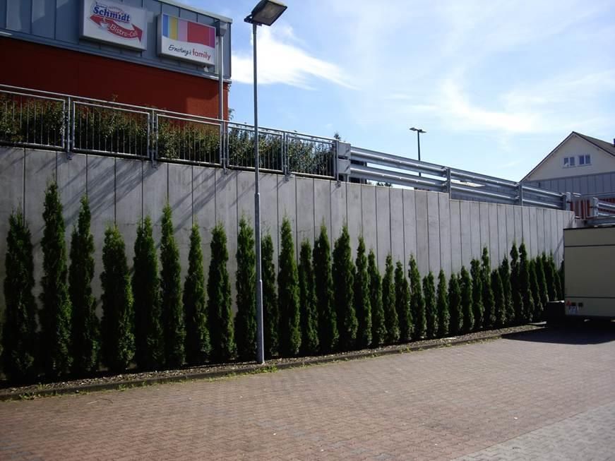 Ein Zaun mit Bäumen vor einem Gebäude, auf dem das Wort „Sport“ steht