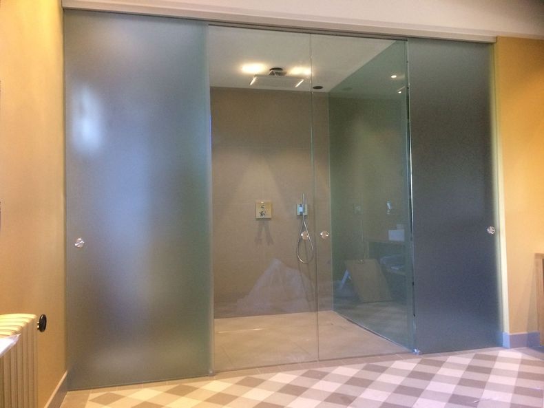 Portes doubles en verre dépoli avec poignées chromées dans un couloir moderne
