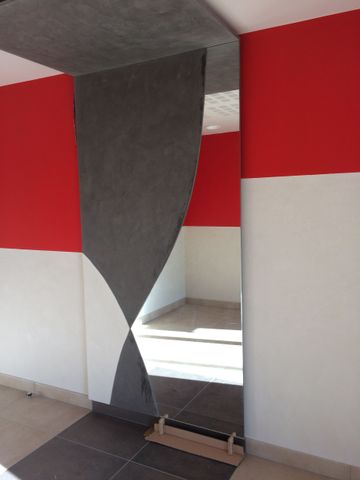 Intérieur aux murs rouges et blancs, avec une alcôve ornée de miroirs et un panneau suspendu sombre au centre.