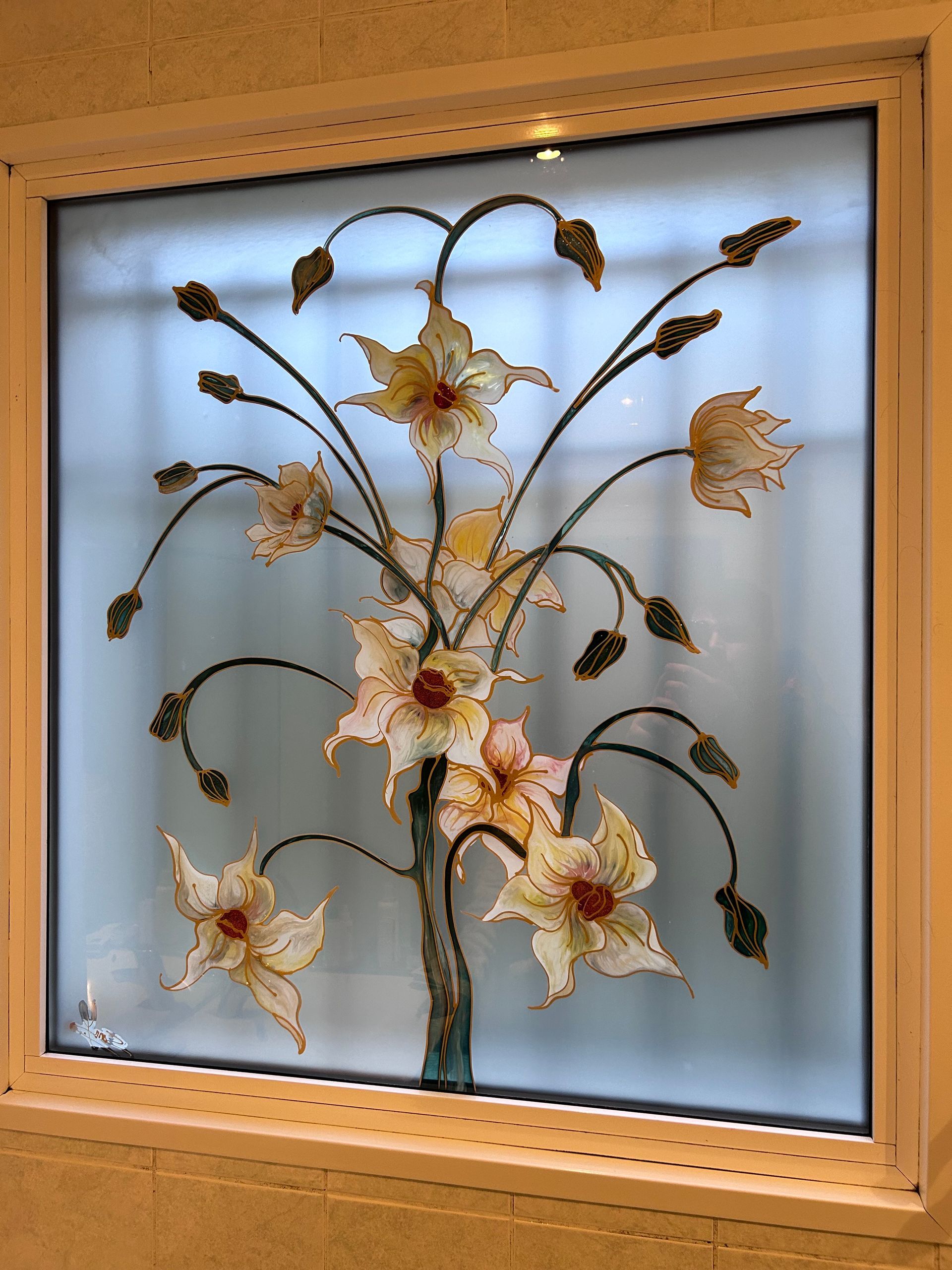 Tableau floral encadré, composé de fleurs crème et or sur verre dépoli, centré dans un cadre en bois.