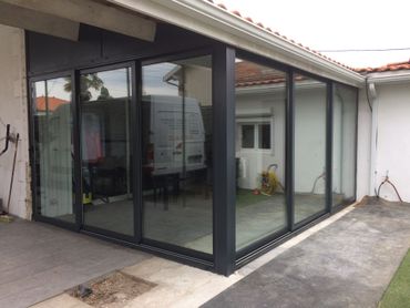 Patio d'une maison moderne avec portes coulissantes en verre à cadre noir et petite cour en béton