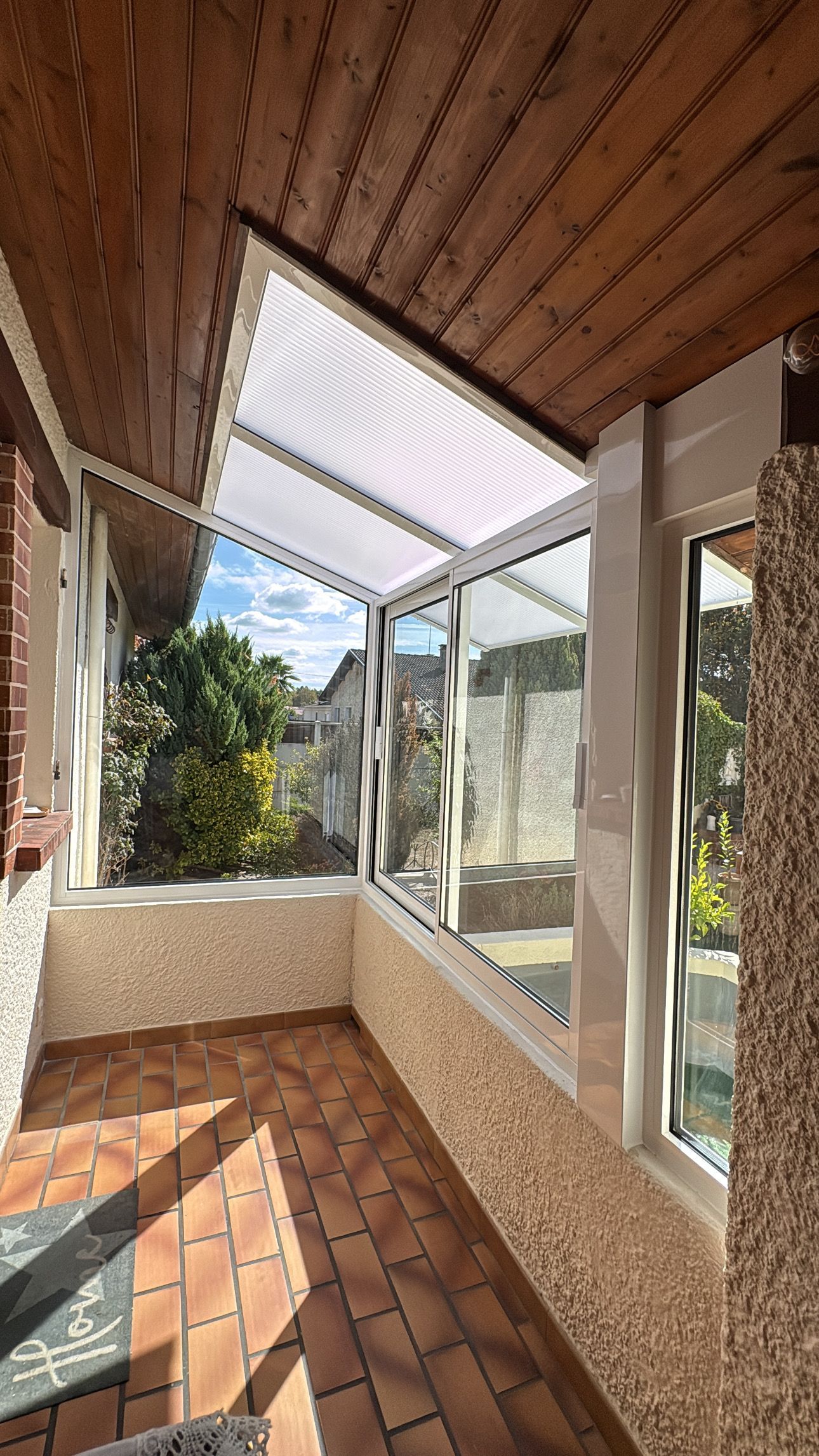 Vue intérieure d'une fenêtre à verre dépoli, bois de chauffage empilé à l'extérieur et radiateur mural blanc en dessous.