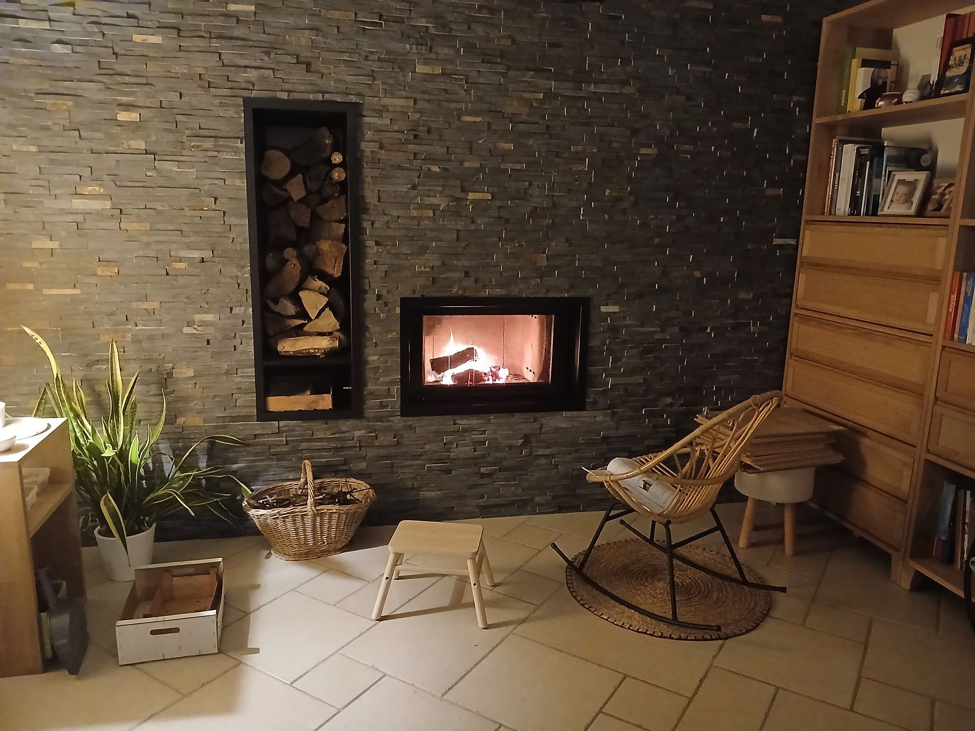 Salon moderne avec cheminée, plafond en bois apparent et coin repas avec de grandes fenêtres.
