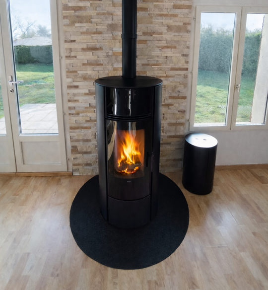 Poêle à bois noir avec un feu dans un coin, avec des murs en pierre et des portes vitrées des deux côtés.