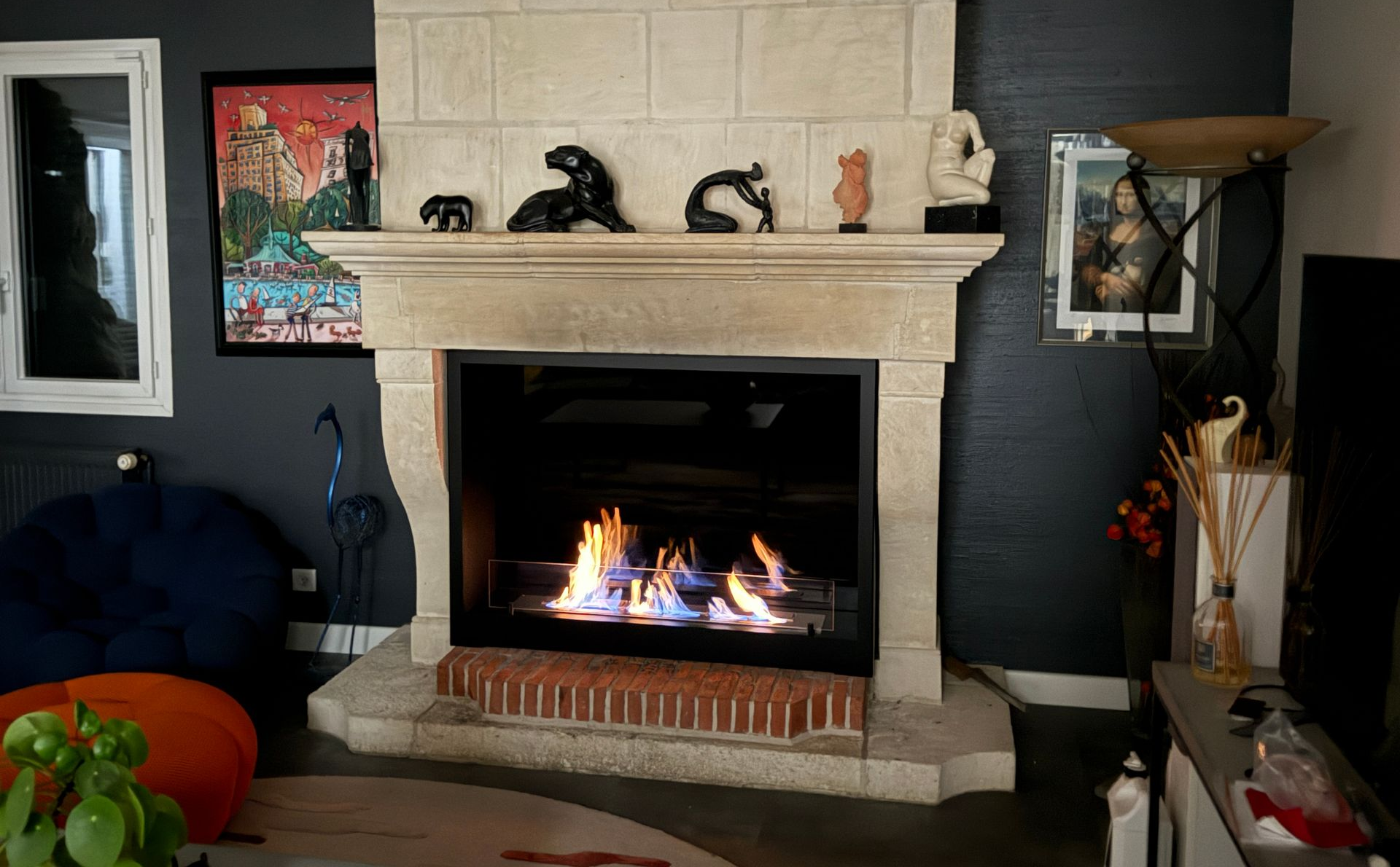 Cheminée noire moderne avec flammes visibles et braises incandescentes dans un salon contemporain.