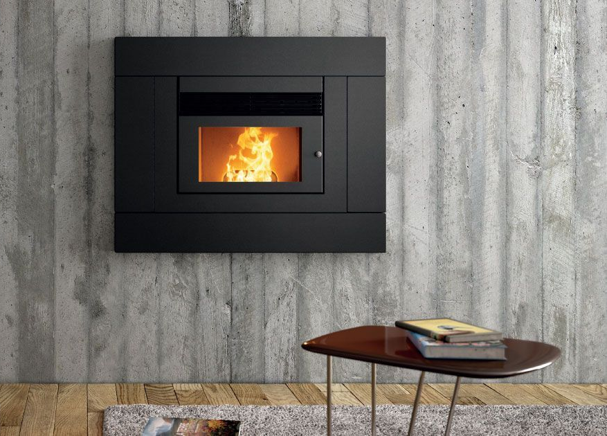 Cheminée moderne encastrée dans un mur en béton, avec une petite table ronde et un livre devant.