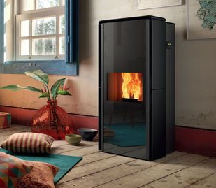 Poêle à granulés noir moderne avec flamme visible dans une pièce confortable près d'une fenêtre et de coussins de sol.
