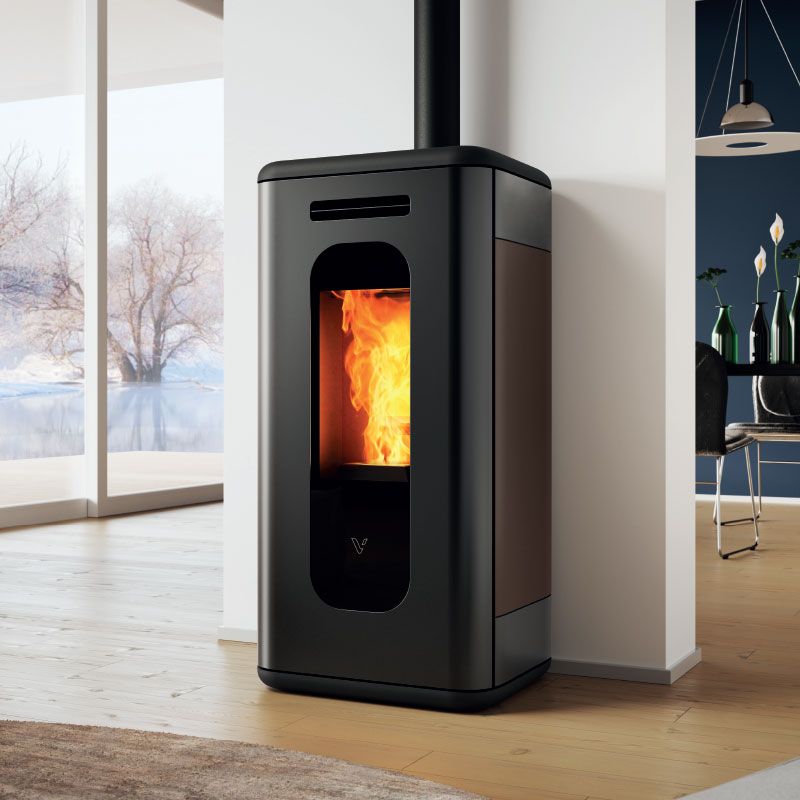 Poêle à granulés cylindrique noir avec un feu crépitant dans une pièce lumineuse près d'une fenêtre.