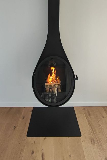Cheminée d'angle blanche moderne avec foyer noir et feu allumé dans un salon.
