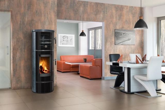Salon moderne avec poêle à bois noir, canapé orange et table à manger blanche dans un intérieur contemporain.