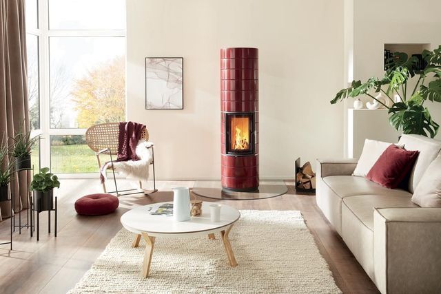 Salon lumineux avec canapé beige, fauteuil rouge, table basse et cheminée rouge.