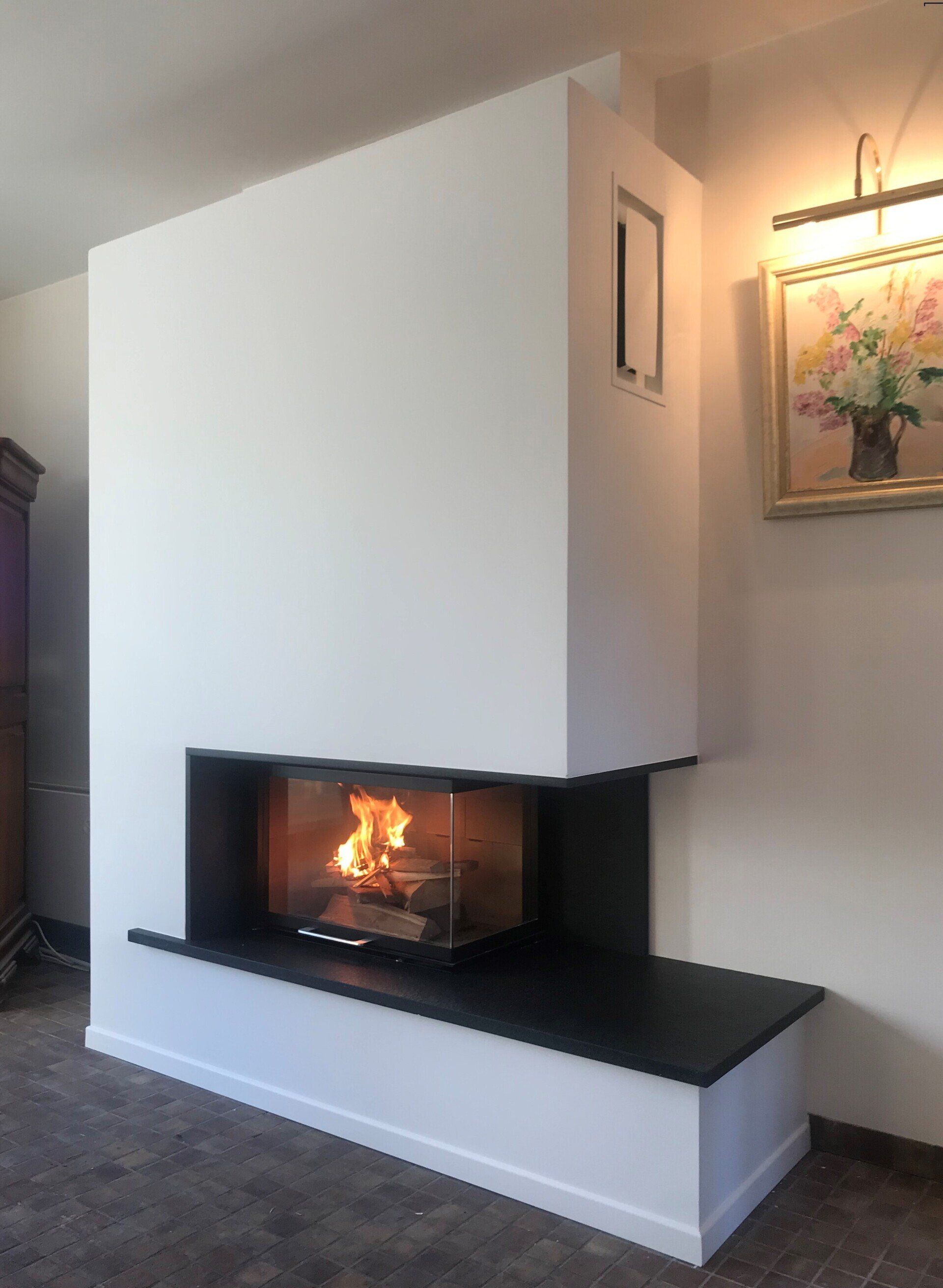 Cheminée d'angle blanche moderne avec feu allumé dans un salon