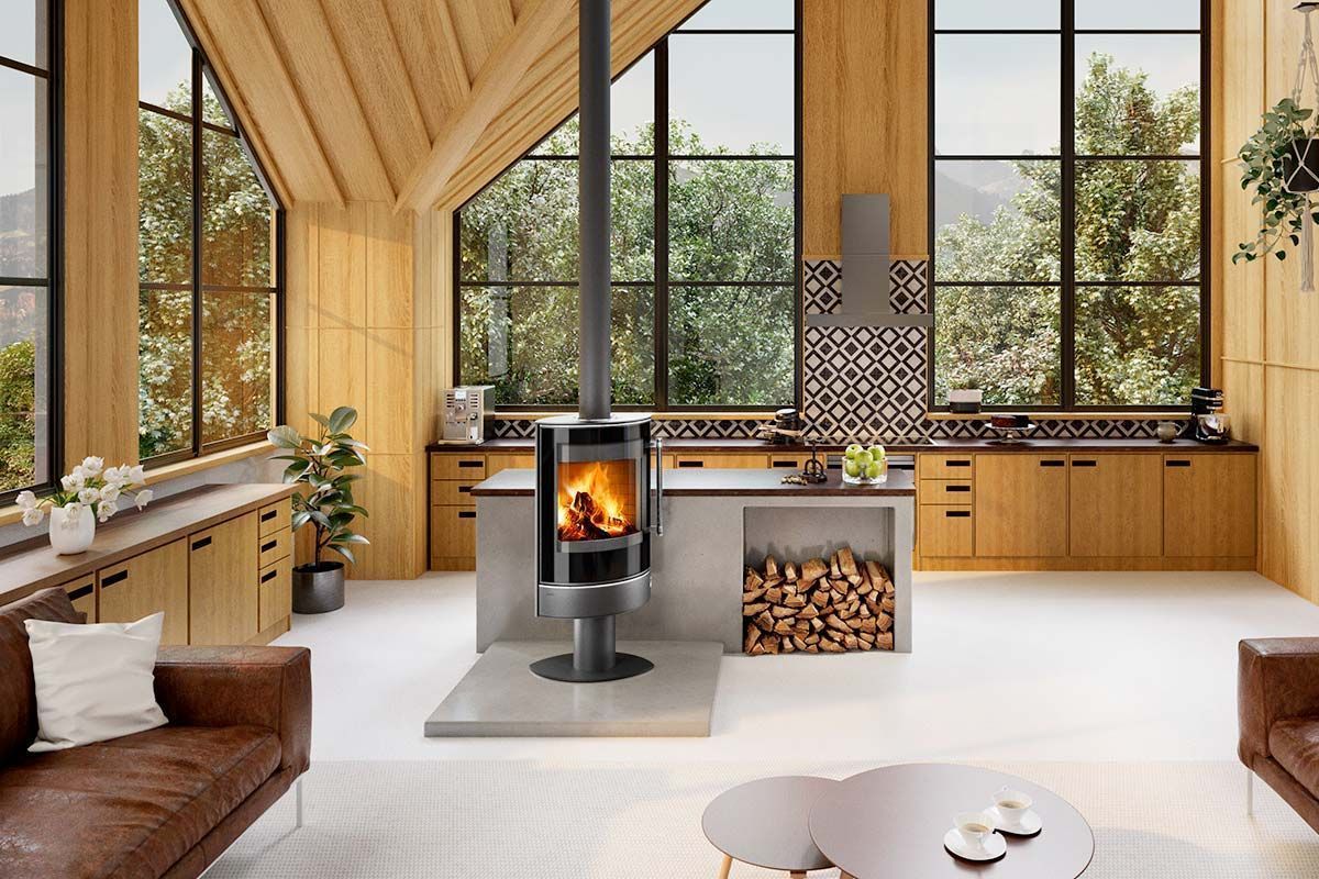 Salon moderne avec plafond en bois, grandes fenêtres et poêle à bois central à côté d'une pile de bois de chauffage.