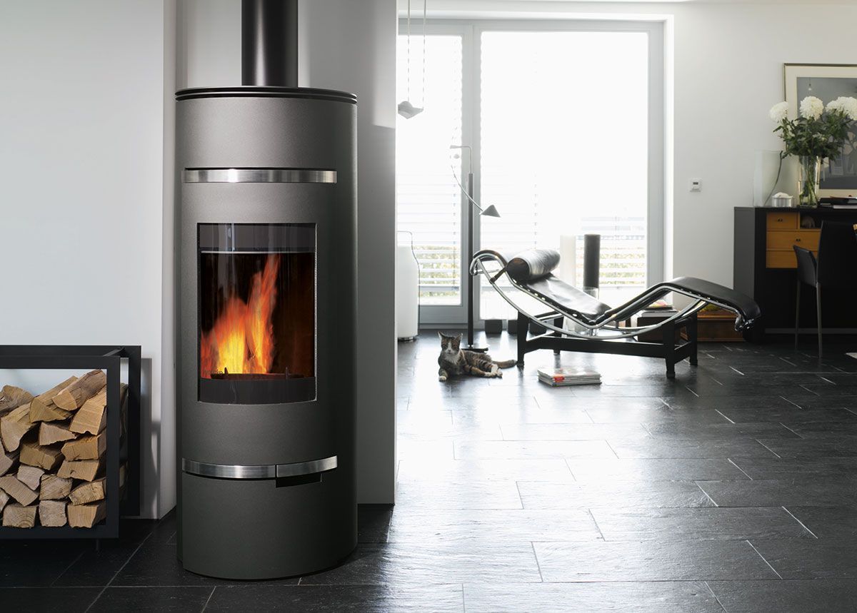 Salon moderne avec un poêle à bois allumé et une pile de bois de chauffage.