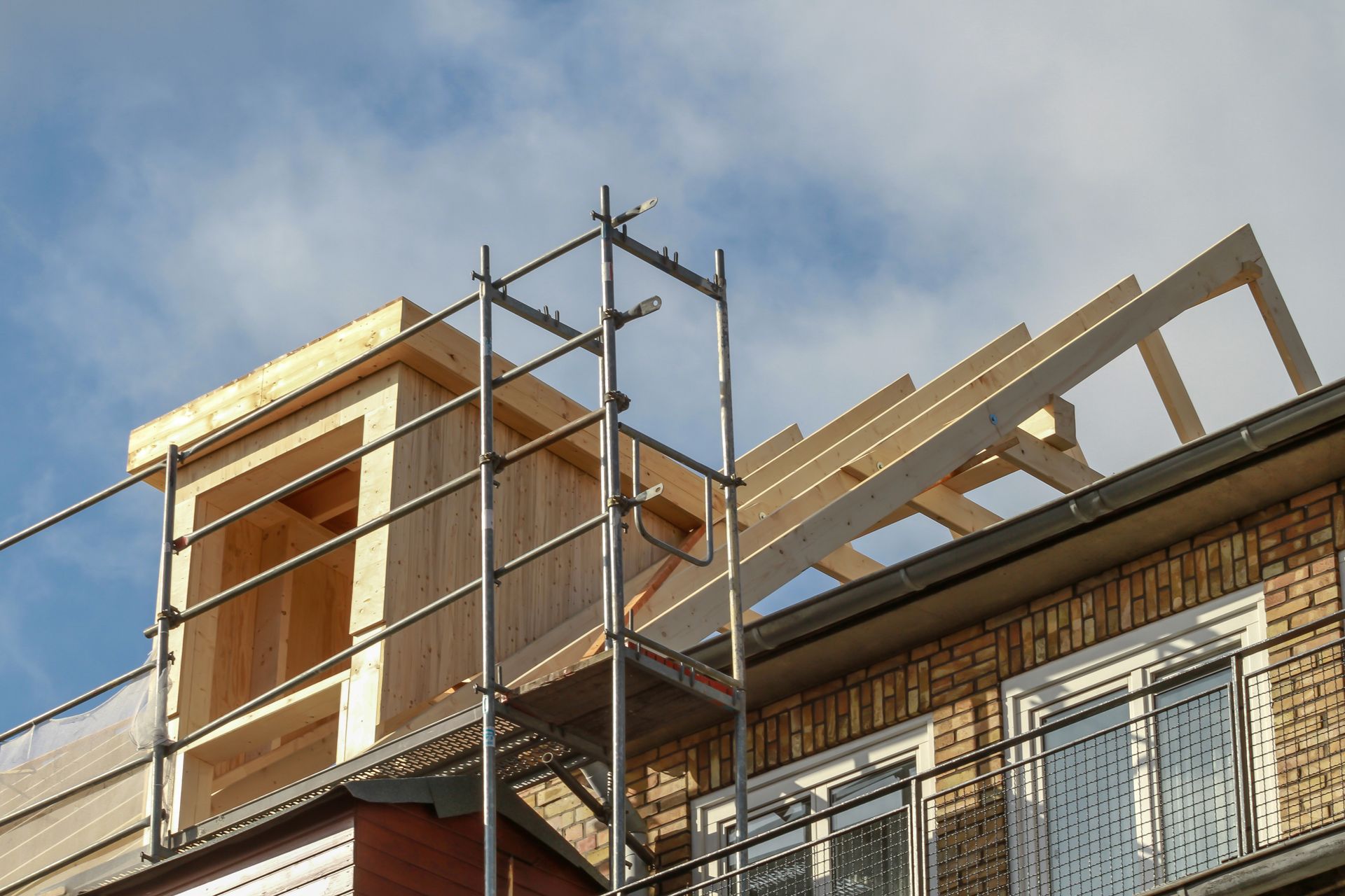 Construction sur un toit d'immeuble avec échafaudage, structure en bois non finie, ciel bleu.