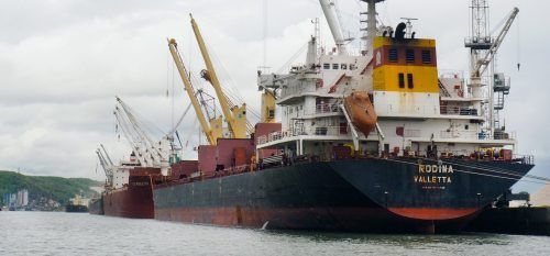 Navire cargo dans un port, avec des grues.