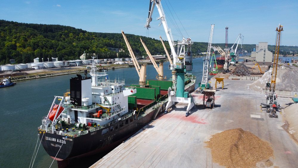 Cargo amarré au port, en cours de chargement par des grues.