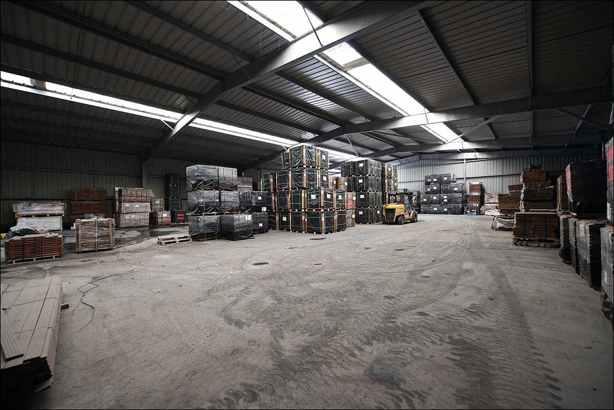 Intérieur d'entrepôt avec matériaux empilés et un chariot élévateur.