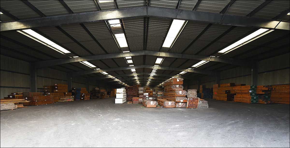 Intérieur d'un entrepôt avec des rangées de produits, éclairé par des lampes fluorescentes suspendues.