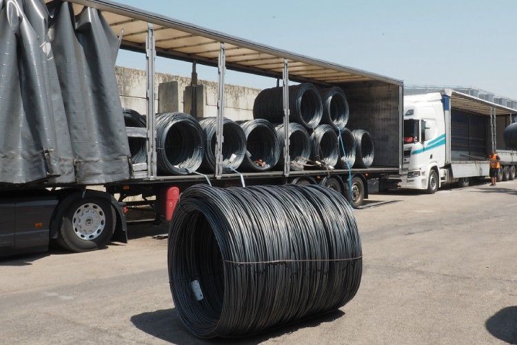 Camions chargés de grandes bobines de fil d'acier noir.
