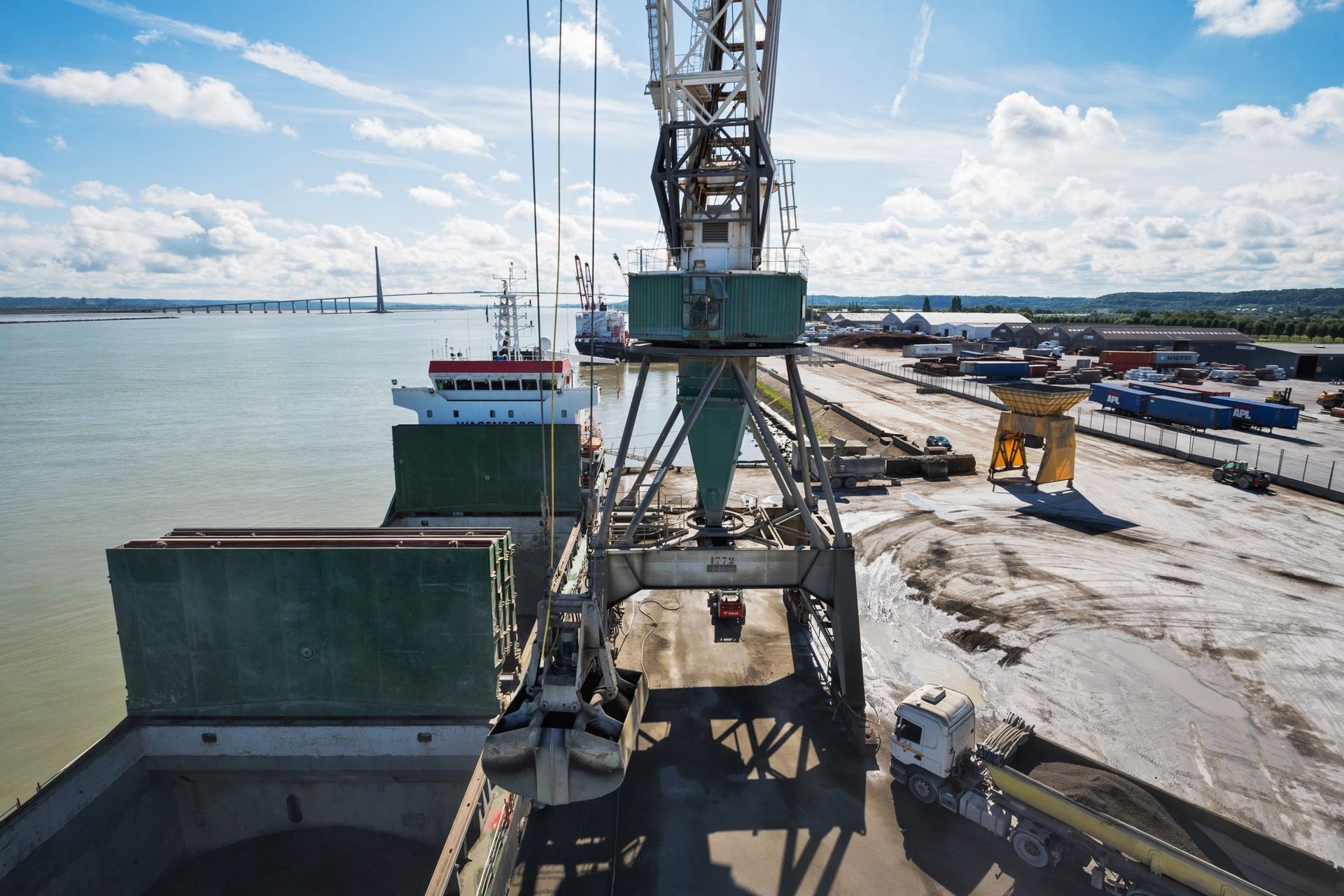 Grue déchargeant la cargaison d'un navire dans un port par une journée ensoleillée.