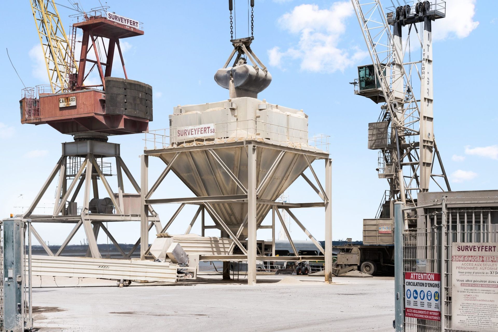 Grues chargeant une cargaison dans une trémie dans un port.