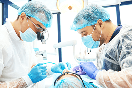 Dos dentistas están trabajando en los dientes de un paciente en un consultorio dental.