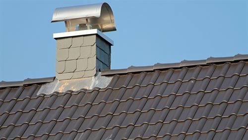 Ein Schornstein auf einem Dach mit einem blauen Himmel im Hintergrund