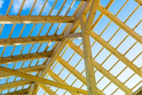 Ein im Bau befindliches Holzdach mit einem blauen Himmel im Hintergrund.