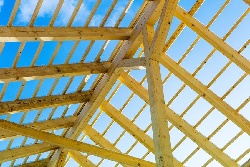 Ein im Bau befindliches Holzdach mit einem blauen Himmel im Hintergrund.