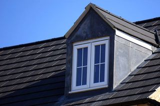 Ein Dach mit einem Fenster darauf und einem blauen Himmel im Hintergrund