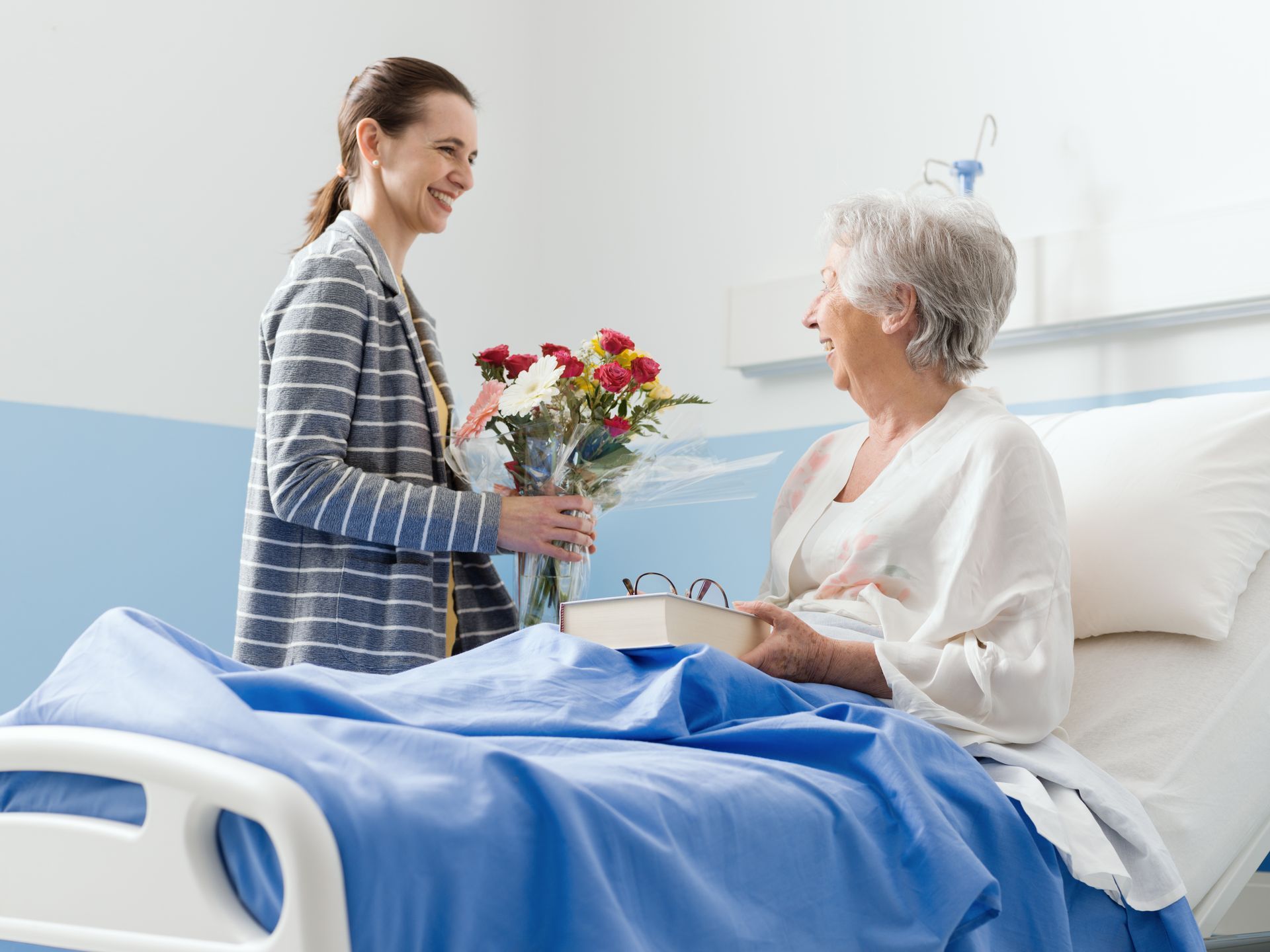 Une femme avec un bouquet de fleurs dans la main et une autre dans un lit d'hôpital