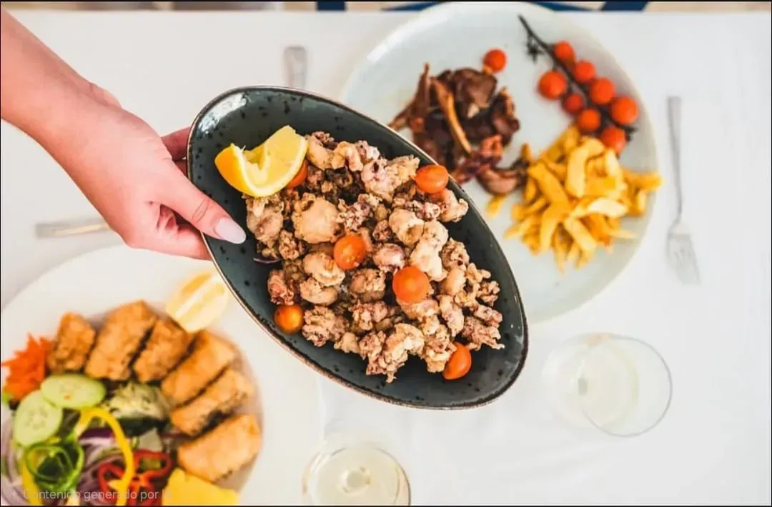 Interior de restaurante con mesas y sillas de madera, paredes de piedra y suelo de baldosas.