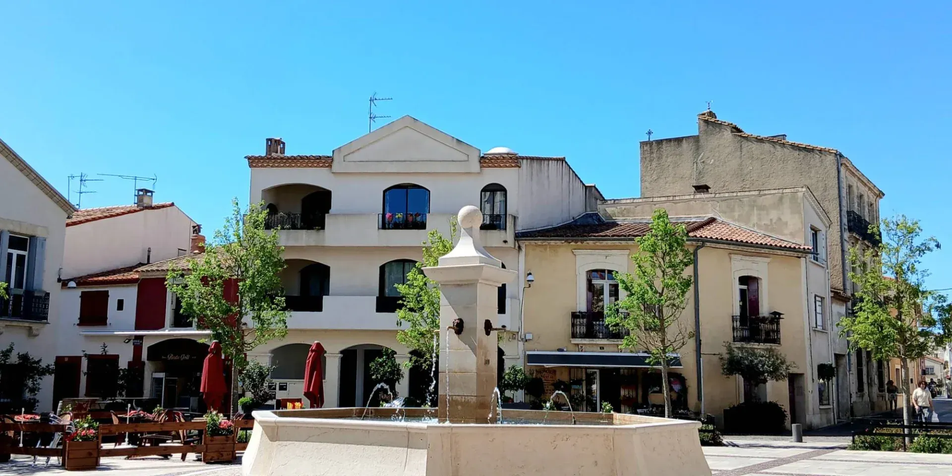 Vue aérienne d'un village dense à flanc de colline, avec ses bâtiments en pierre aux toits de tuiles, entouré d'une forêt verdoyante luxuriante.