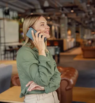 Una mujer con una camisa verde está hablando por un teléfono celular.